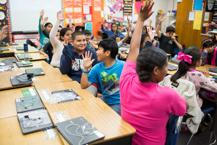 Group of students in class with their hands raised