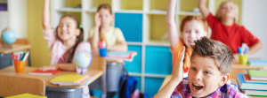 Children in classroom with hands up