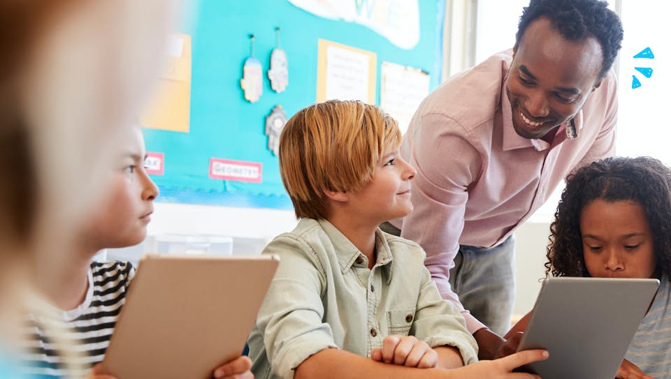 Teacher smiling with students with computers in a classroom
