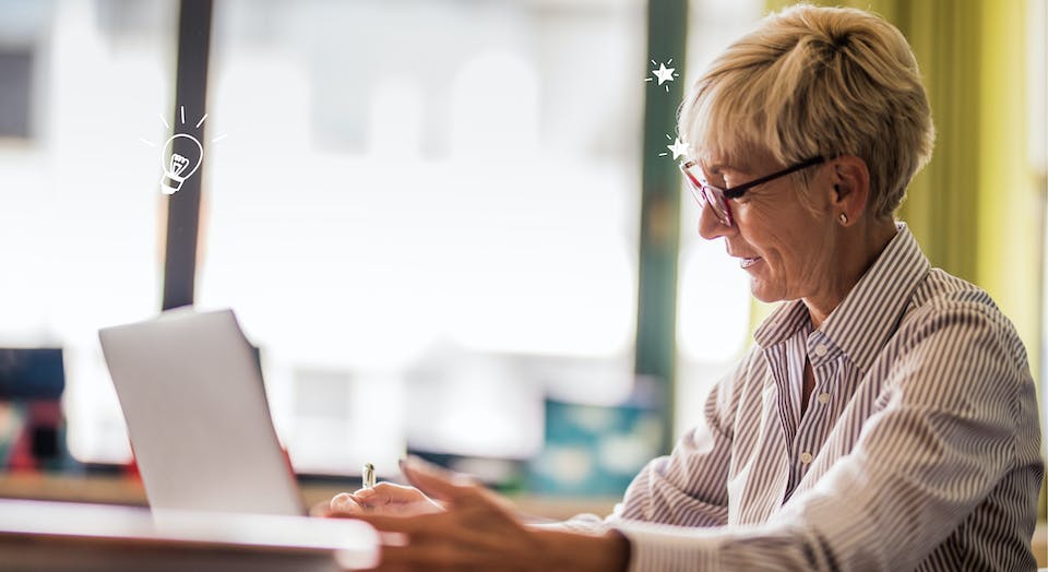 Educator with glasses smiling and writing with a pen