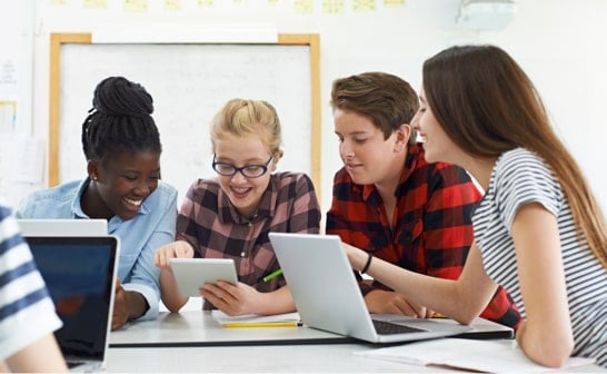 Élèves adolescents travaillant ensemble sur une tablette en classe