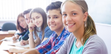 5 élèves en cours nous regardent en souriant