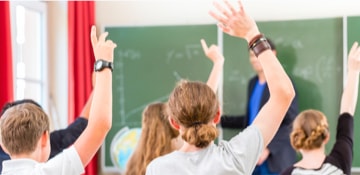 5 élèves lèvent la main pour répondre à la question de leur enseignant