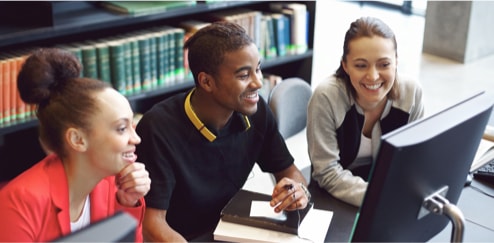 3 élèves à la bibliothèque travaillant à l'ordinateur