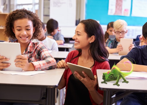 Un enseignant avec un iPad sourit et explique quelque chose à un élève souriant