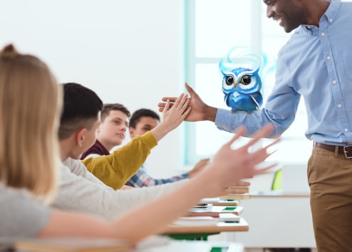 Enseignant avec un hibou de Classcraft sur son bras fait un "Tope là!" à un élève