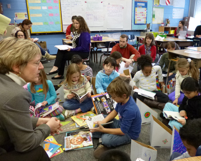 Teacher presenting to young students sitting on a carpet