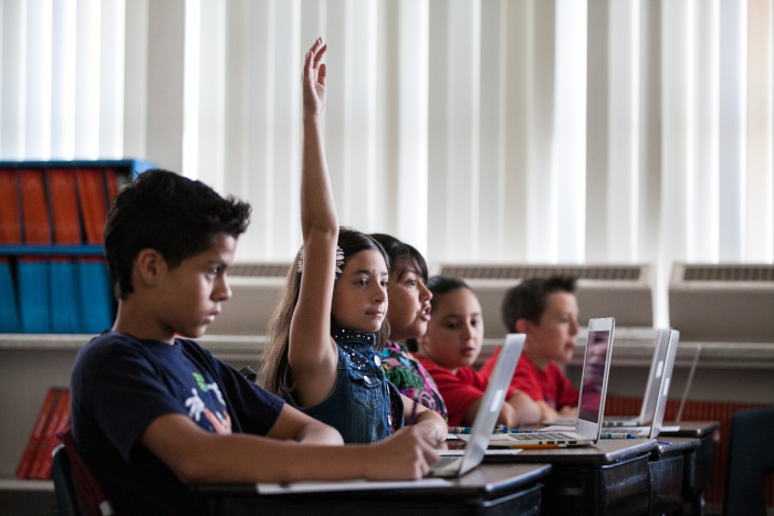 Row of students with little girl raising her hand. 