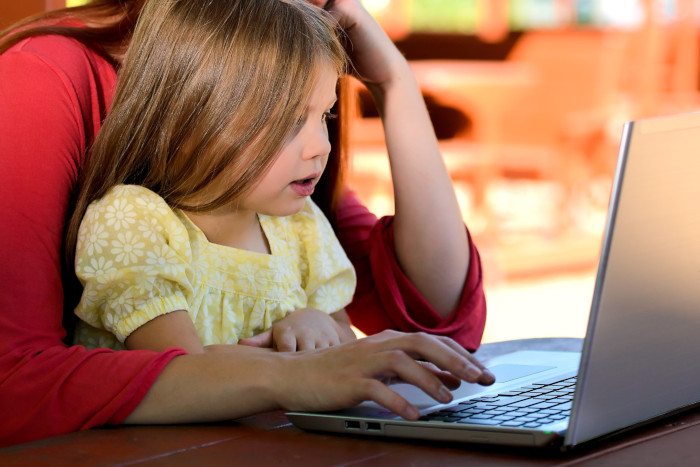 Little girl on the computer with an adult